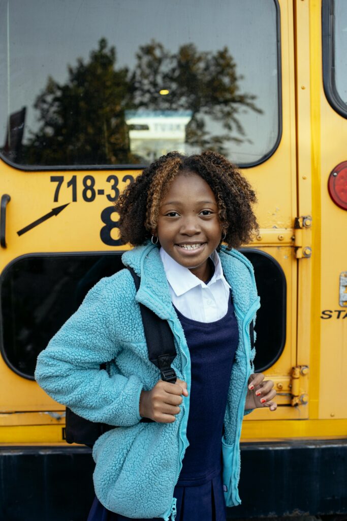 girl standing near a school bus